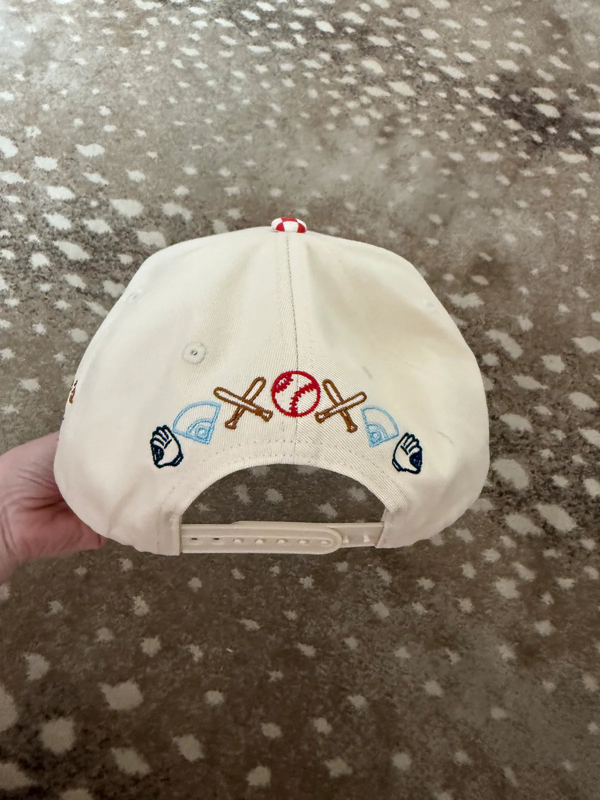 White cap with colorful symbols held against a patterned background