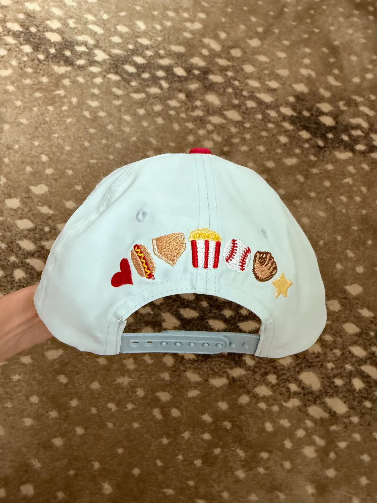 White cap with colorful embroidered designs on a brown surface