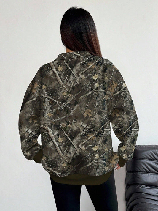 A person shown from the back wearing a camouflage jacket with a woodland tree-bark and leaf pattern in shades of brown, green, and gray, paired with black pants.