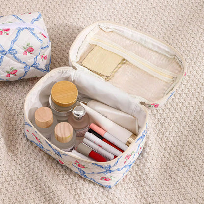 Heart-shaped makeup bag with cosmetic items on a textured surface