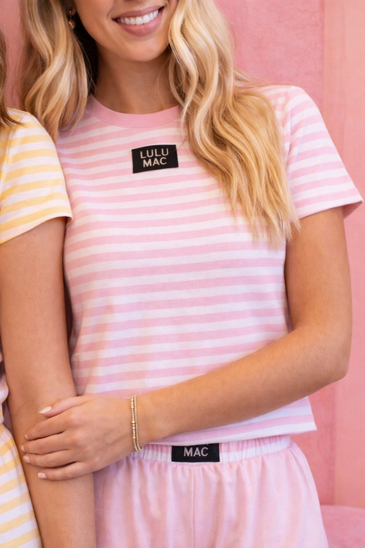 Two people wearing pink striped outfits with visible brand labels against a pink background