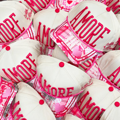 White and pink hats with 'AMORE' text and heart designs.