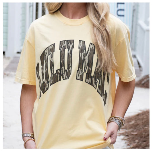 Person wearing a yellow t-shirt with text, standing outdoors.