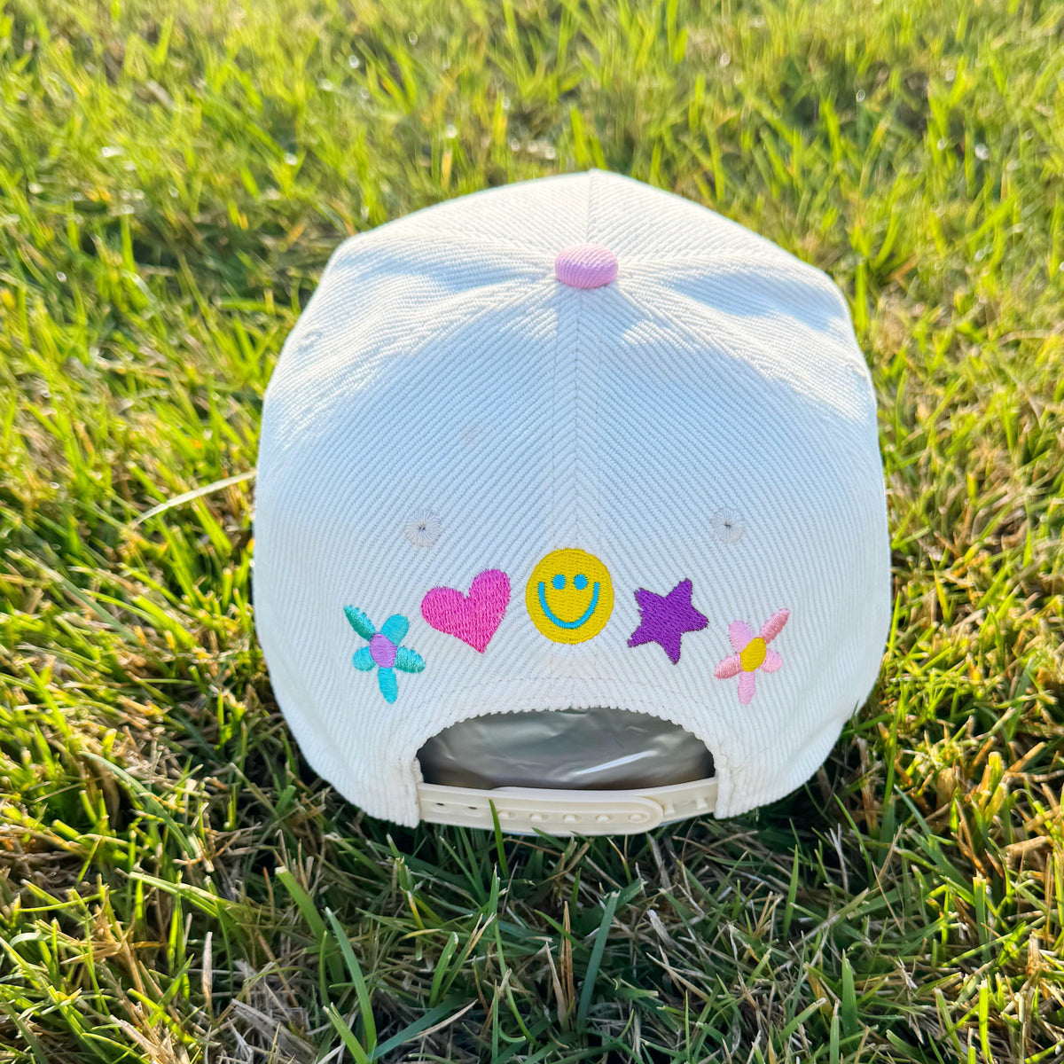 White cap with colorful designs on a grassy background