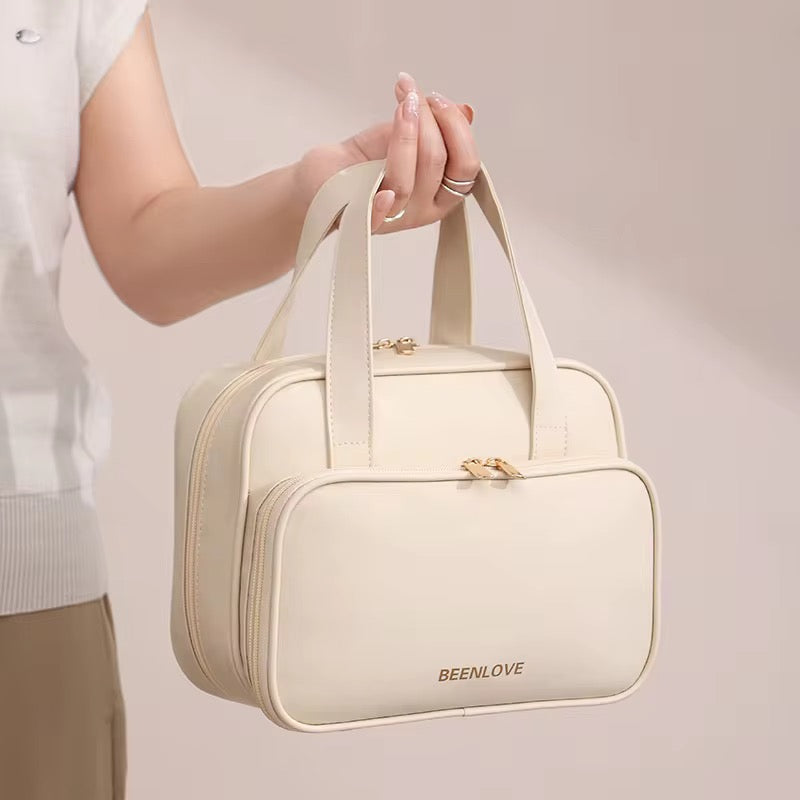 Beige handbag held by a person with 'BEENLOVE' branding on a plain background