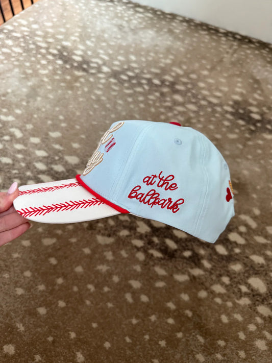 Light blue baseball cap with red stitching and text held on a patterned surface