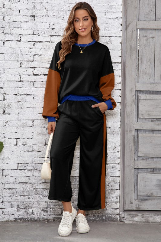 Woman wearing a black and brown outfit with white sneakers against a white brick wall.