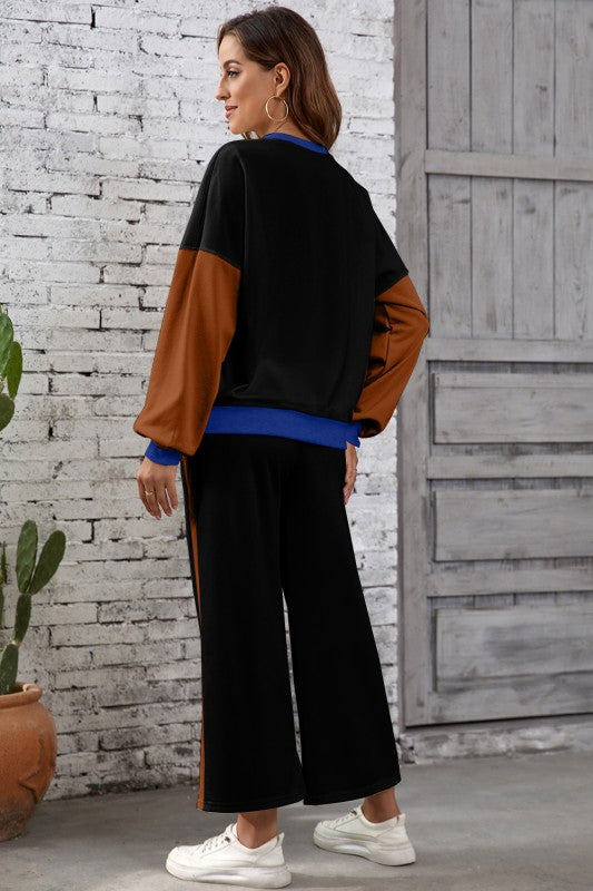 Woman wearing a black and brown color-blocked outfit with white sneakers, standing against a textured wall.