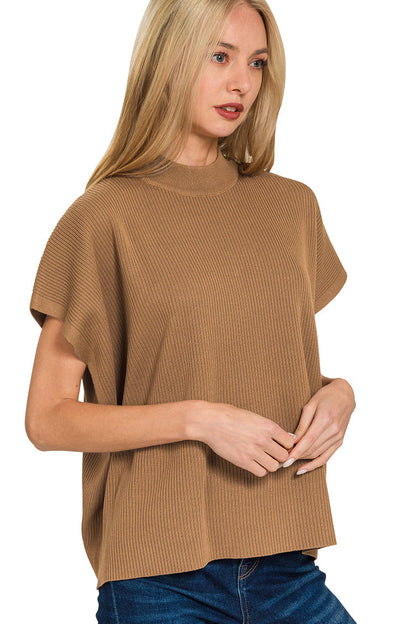 A woman wearing a camel brown ribbed knit short-sleeve top with a mock neck, paired with blue jeans, against a plain white background.
