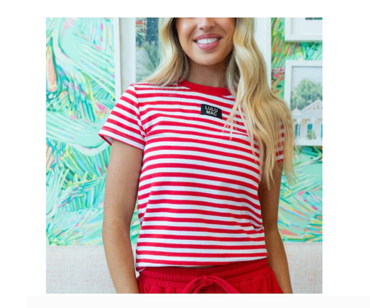Person wearing a red and white striped shirt with a logo, standing in front of a colorful abstract painting.