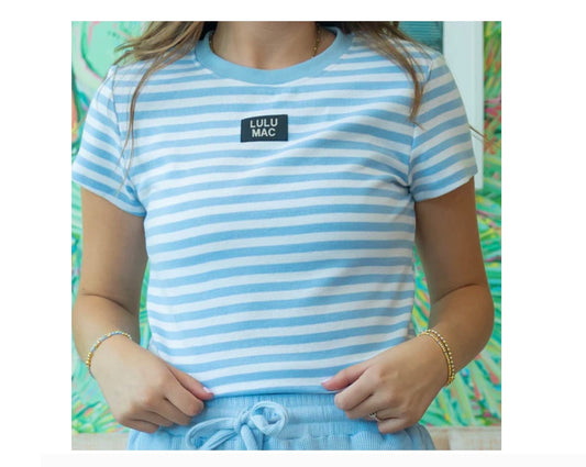 Person wearing a blue and white striped shirt with 'Lulu Mac' logo, standing against a colorful background.