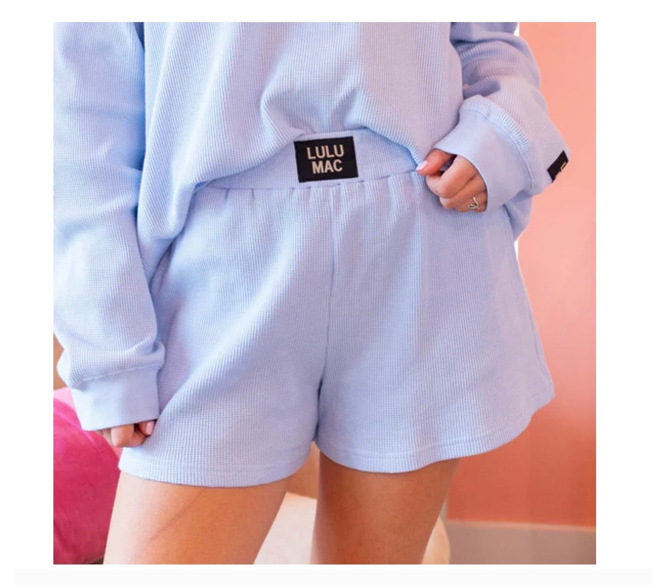 Light blue sweatshirt and shorts with a visible brand label on a plain background