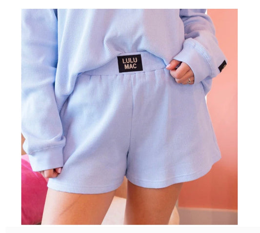 Light blue sweatshirt and shorts with a visible brand label on a plain background