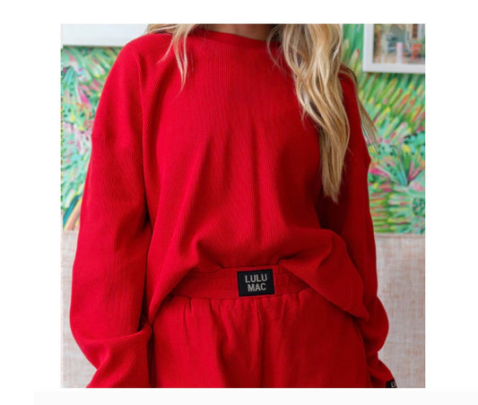 Red outfit with a visible brand label against a colorful abstract painting background