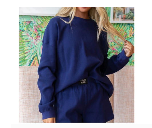 Person wearing a navy blue outfit with a visible brand logo against a colorful abstract painting.