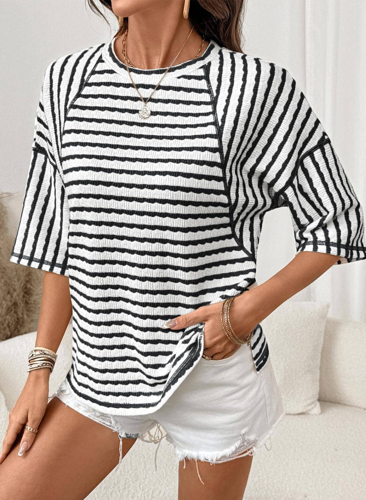 Woman wearing a black and white striped shirt with white shorts in a casual setting.