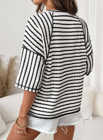 Person wearing a black and white striped sweater in a casual setting